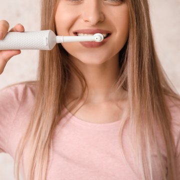 Girl brushing her teeth with an Electric toothbrush 